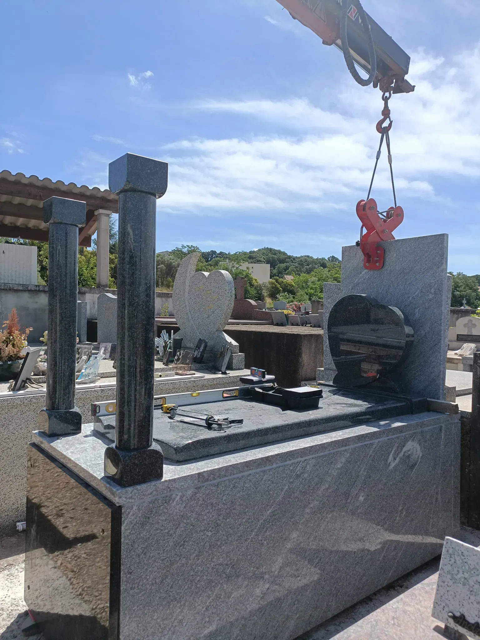 Montage d'une chapelle funéraire en granit à l'aide d'un camion grue.